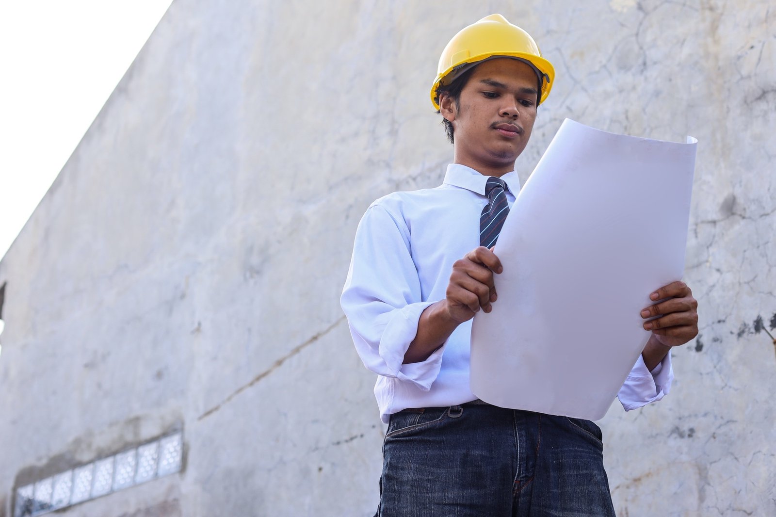 Serious civil engineer working with documents on construction site.